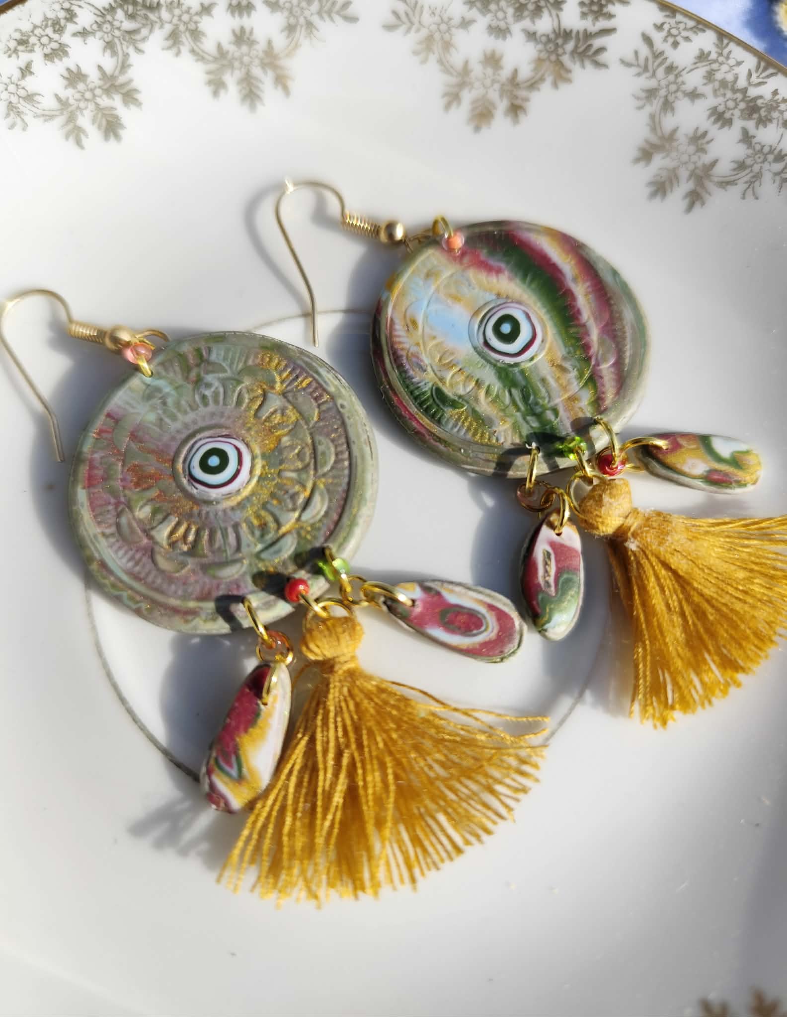 Boucles d’oreilles veilleuses bohèmes rondes en argile polymère avec pompon doré et breloques colorées faites main.